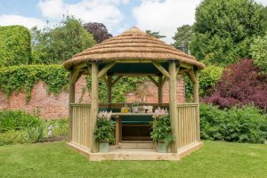 Forest Garden 3.6m Hexagonal Wooden Garden Gazebo with Thatched Roof - Furnished with Table, Benches and Cushions (Green)
