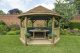 Forest Garden 4m Hexagonal Wooden Garden Gazebo with Thatched Roof - Furnished with Table, Benches and Cushions (Green)